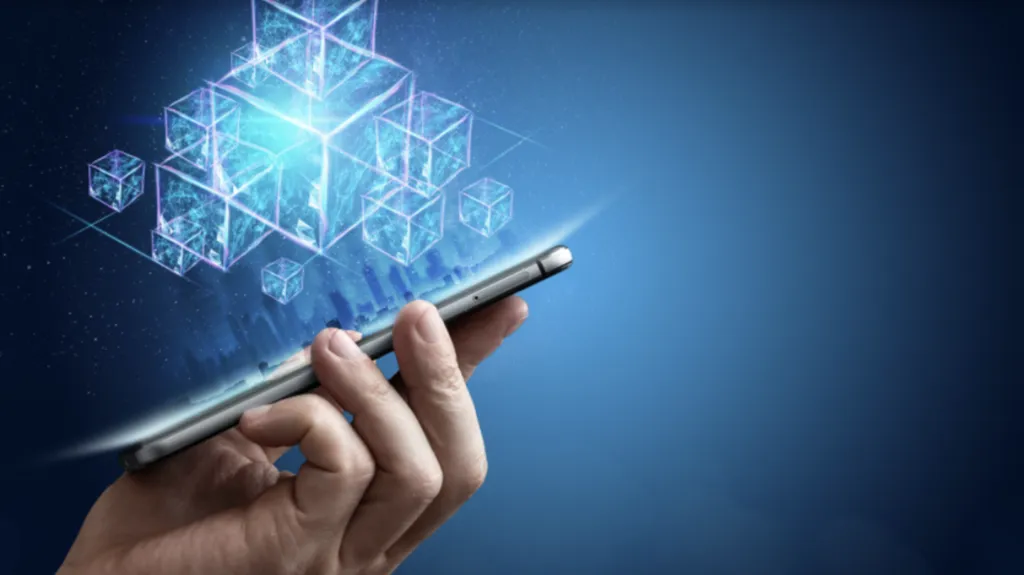 a hand of a person holding a smartphone and on it a hologram of blockchain technology